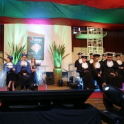 Treze pessoas de toga em um palco decorado.