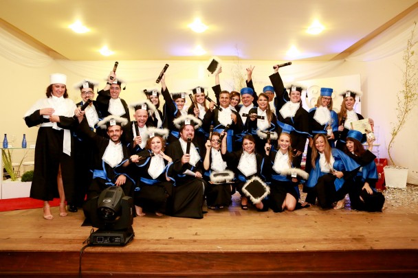 Formandos dos cursos de Artes da Uergs comemorando a obtenção do grau acadêmico, com os canudos nas mãos.