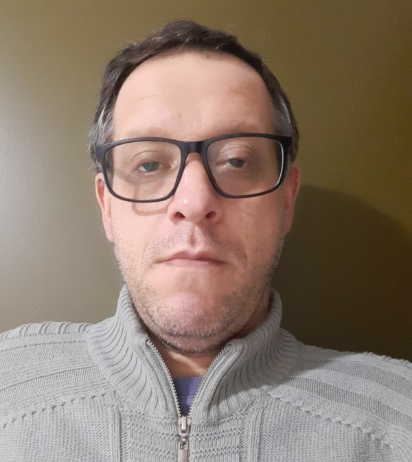 Homem branco, de cabelhos grisalhos e semblante sério, usao óculos de grau.